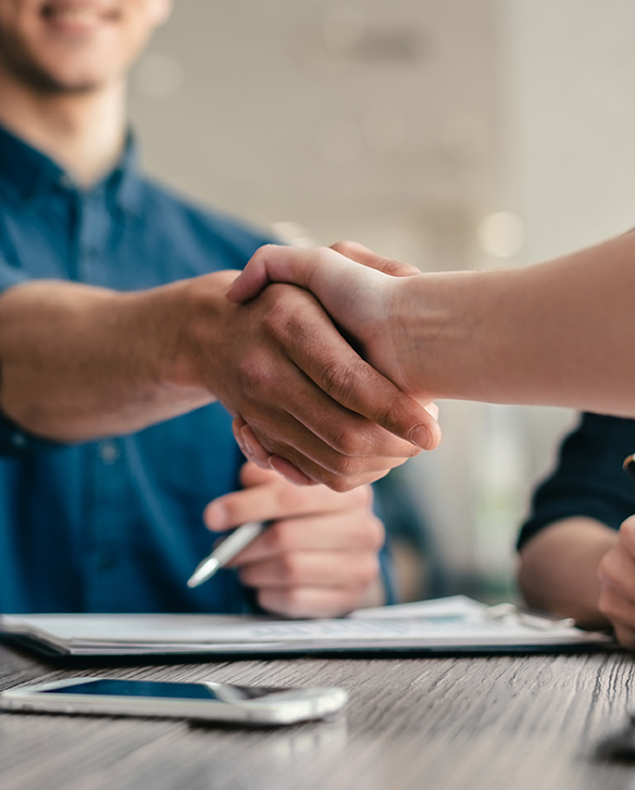 Two people shaking hands across a desk