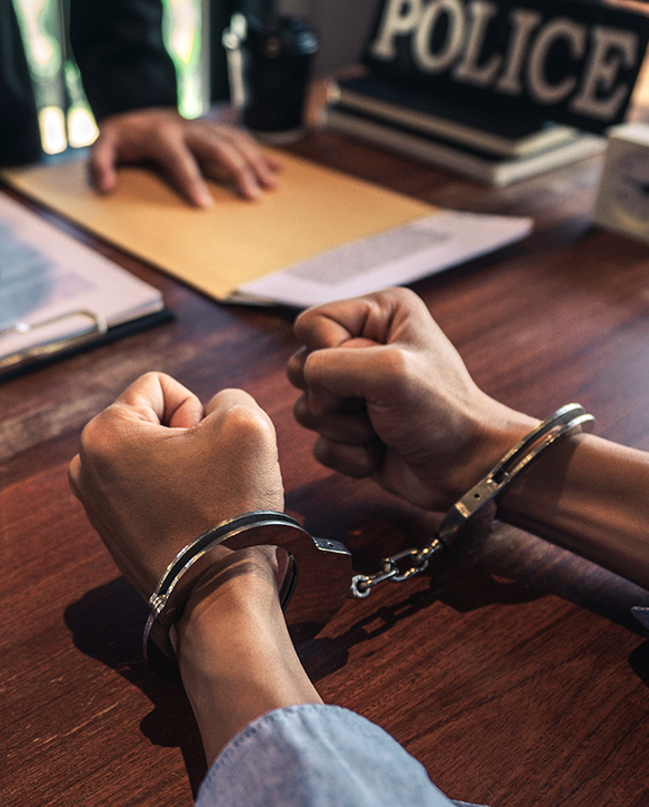 Handcuffed person seated at a police desk