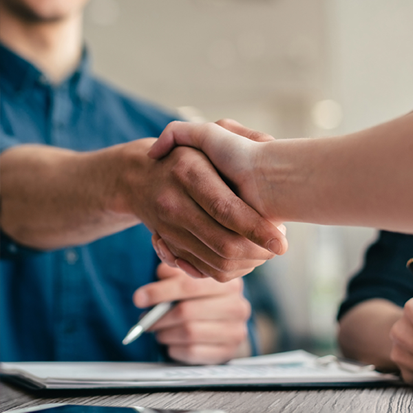 Two people shaking hands across a desk