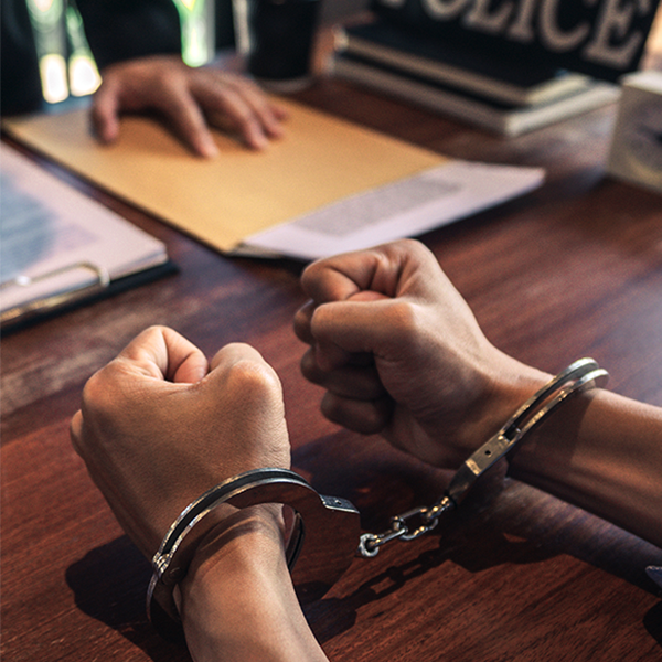 Handcuffed person seated at a police desk