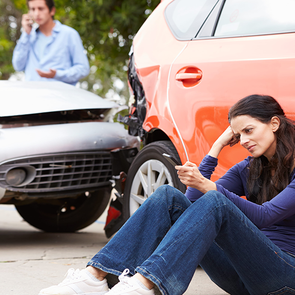 Driver seated beside a car after a collision